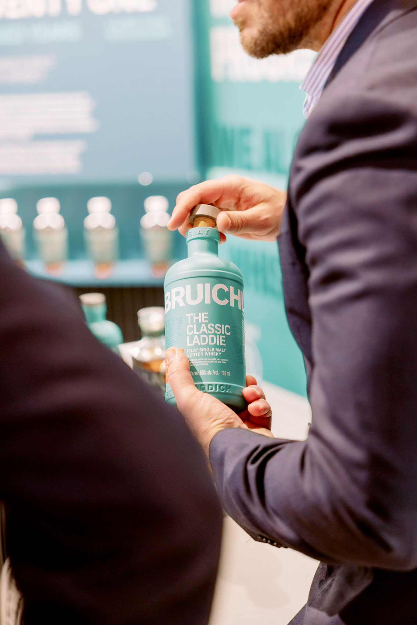 Close-up of a person holding a Bruichladdich The Classic Laddie bottle at the Rémy Cointreau exhibition stand in Cannes, produced by Beautiful LFP.