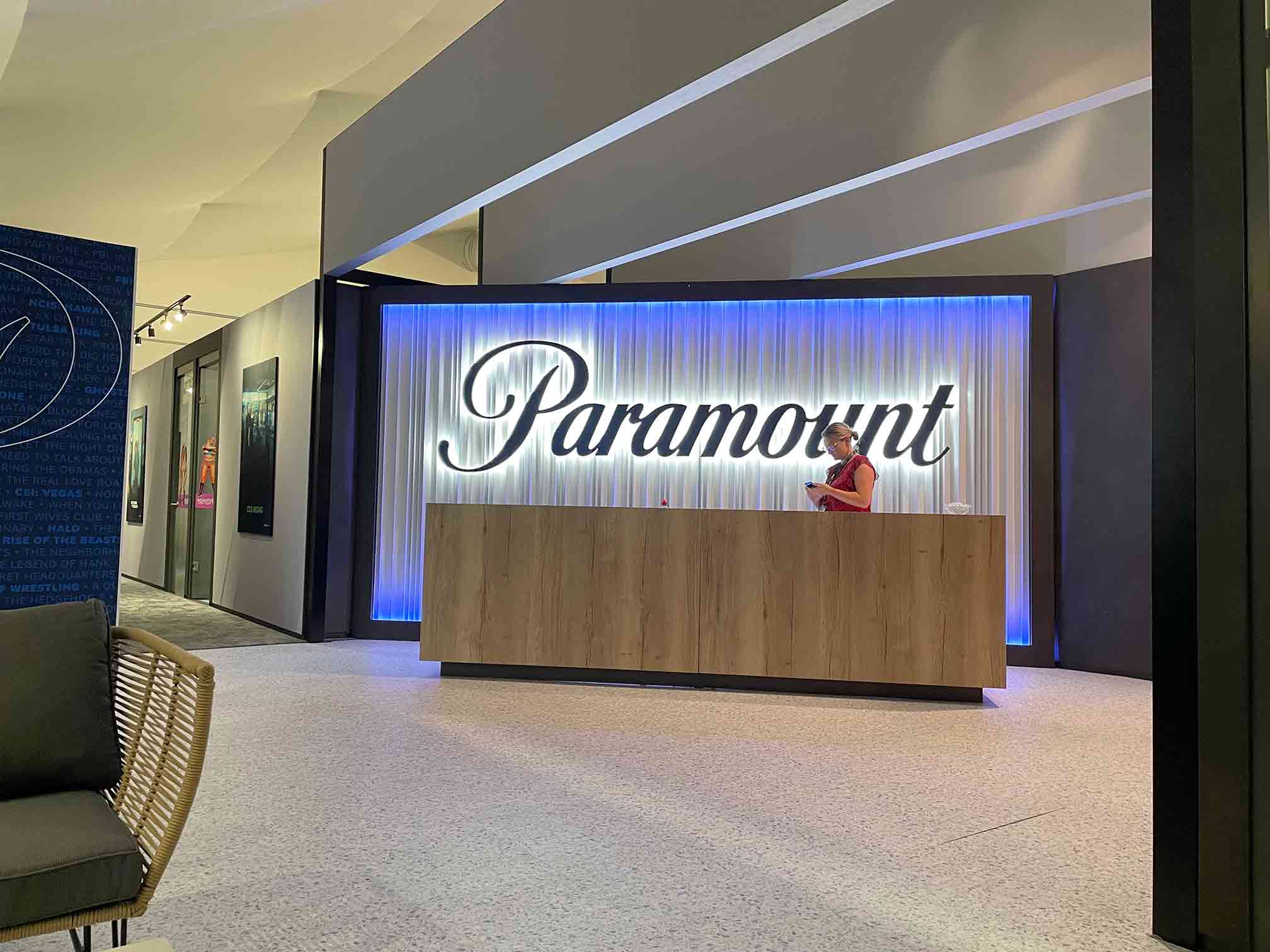Paramount exhibition stand reception area with illuminated logo and backlit feature wall by Beautiful LFP.