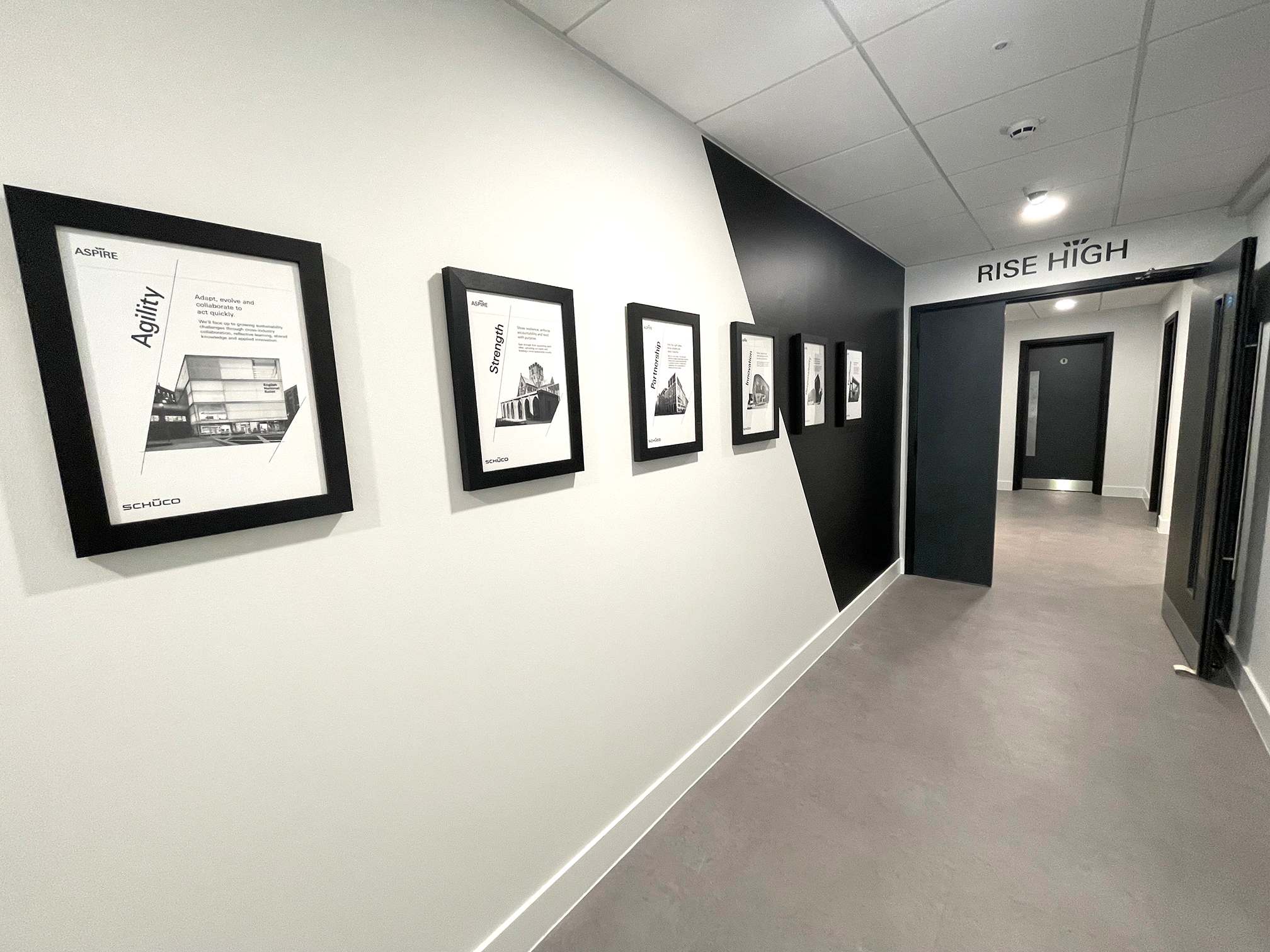 Schüco UK corridor interior branding installation in Milton Keynes featuring framed corporate values wall graphics and Rise High typography